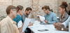 a group of people look at some documents together in a room